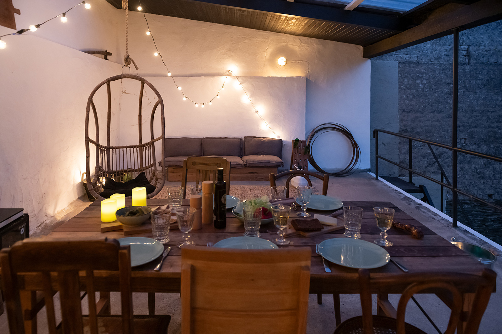 Außenbereich Terrasse:  Gedeckter Tisch vor Lounge-Möbeln bei Dämmerung stimmungsvoll beleuchtet